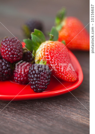 red juicy strawberry and blackberry in red plate on a wooden sur red juicy strawberry and blackberry in red plate on a wooden sur 10156687