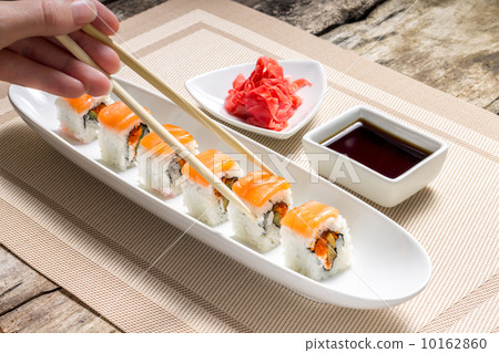 Eating with chopsticks seafood sushi rolls with traditional spices 10162860