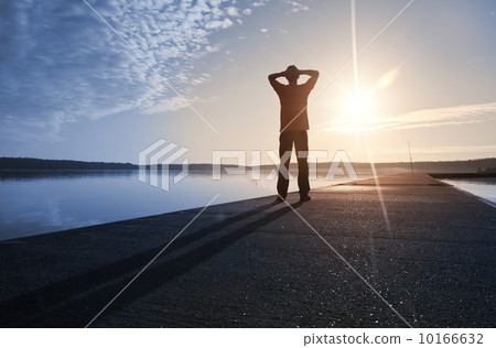 A man stands on the concrete pier starring at the Sun A man stands on the concrete pier starring at the Sun 10166632
