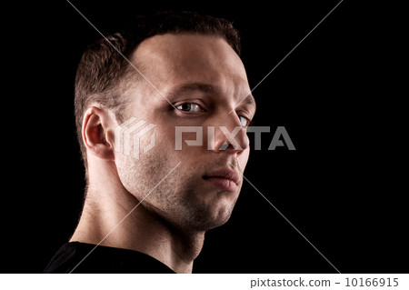 Haughty young Caucasian man's portrait. Close-up face isolated on black 10166915