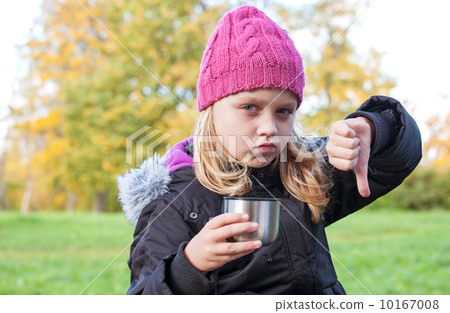 little beautiful blond girl drinks tea in autumnal park and showing thumbs down little beautiful blond girl drinks tea in autumnal park and showing thumbs down 10167008