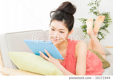 A woman who operates a tablet with a sofa 10171944