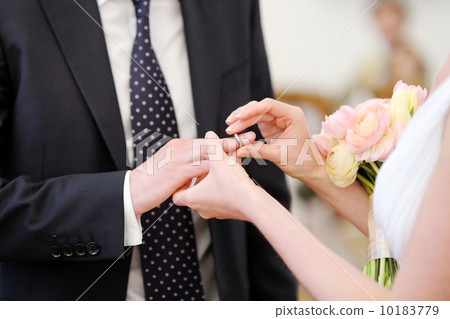 Bride putting the ring on groom's finger 10183779