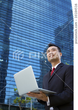 Asian businessman working outdoors with a laptop computer. 10184516