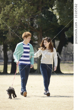 A young couple walking a dog 10185582