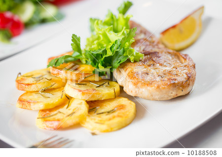 Roasted pork chop with potatoes on dish 10188508