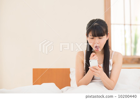 有一個智能手機的一名婦女在床上 10200440