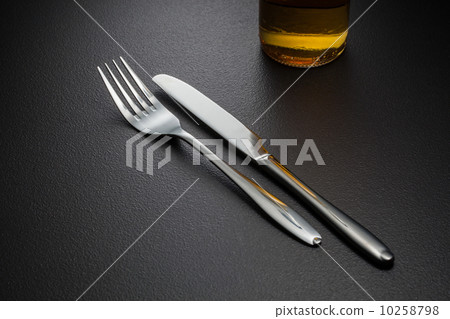 bottle of beer, knife and fork on black 10258798