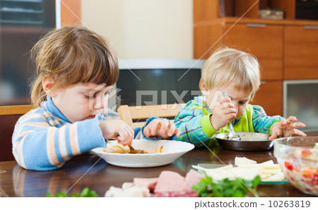 Baby girls eating at wooden table Baby girls eating at wooden table 10263819