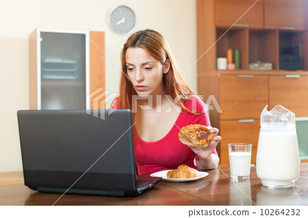 Young famale checking e-mail on laptop during breakfast time 10264232