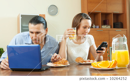 Couple using devices during breakfast time 10264252