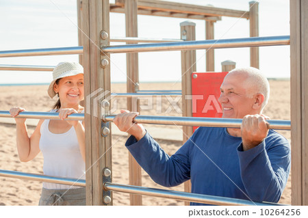 senior man and mature woman training with pull-up bar 10264256