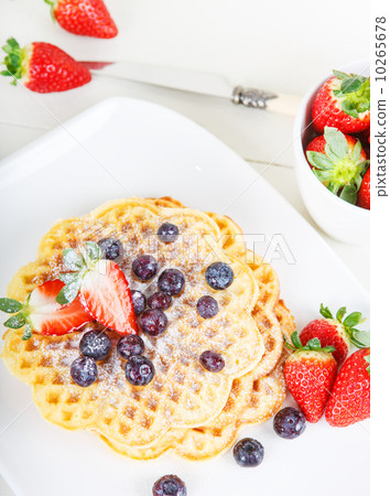 Crisp golden fresh baked waffle topped with strawberries on whit Crisp golden fresh baked waffle topped with strawberries on whit 10265678