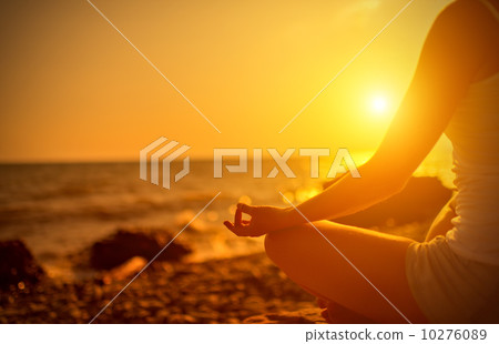 hand of  woman meditating in a yoga pose on beach at sunset 10276089