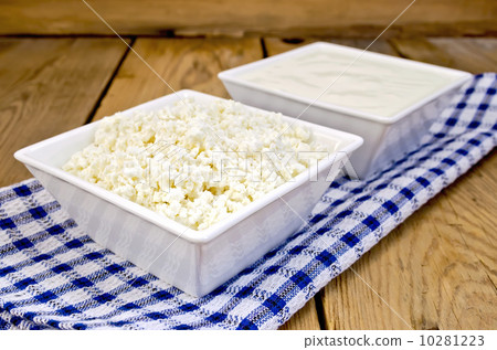Curd and sour cream in bowls on board with napkin 10281223