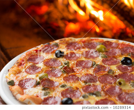 Traditional pizza with salami , capers and olives baking in oven 10289314