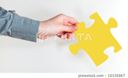 female hand holding yellow puzzle piece 10326867
