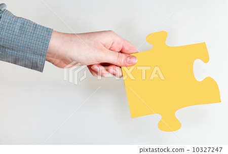 female hand holding yellow puzzle piece female hand holding yellow puzzle piece 10327247