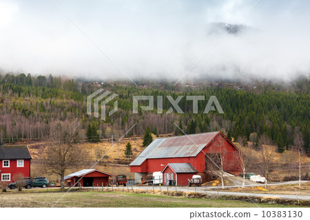 Rural Norwegian landscape with red wooden houses and clouds on h 10383130