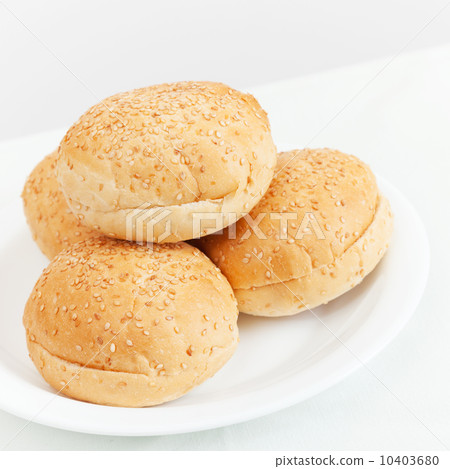 Four small buns for hamburgers lay on white plate 10403680