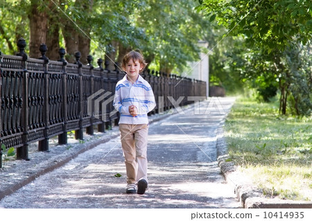 Little boy walking on a sunny street 10414935