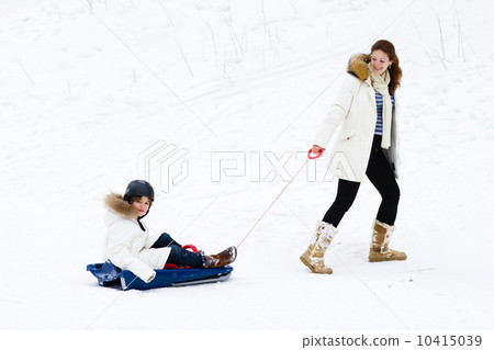 Young beautiful mother and her school age son enjoying a sleigh 10415039