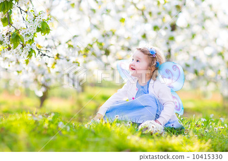 Curly toddler girl in fairy costume playing in fruit garden 10415330