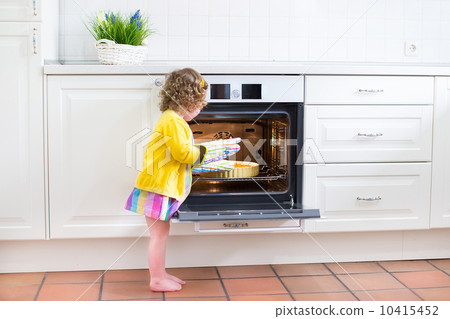 Toddler girl with an apple pie in the oven 10415452