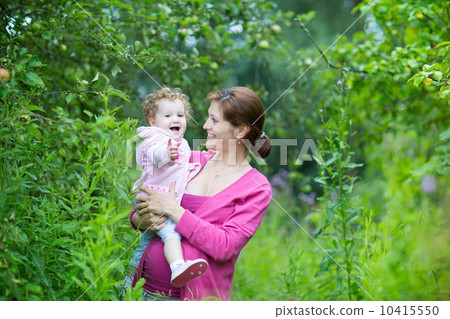 Beautiful pregnant mother playing with her one year old baby dau 10415550