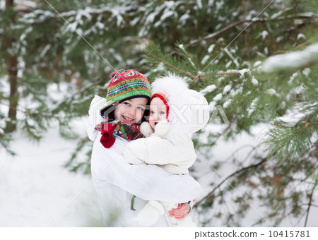Brother and baby sister walking in a forest on a snowy winter day 10415781