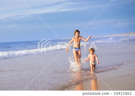 Adorable baby girl wearing a diaper and her brother running toge 10415801