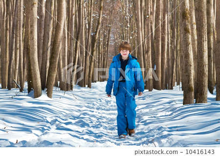 Cute boy walking in a snowy forest on a cold sunny day Cute boy walking in a snowy forest on a cold sunny day 10416143