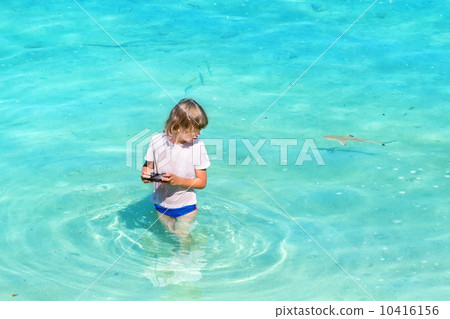 Little boy playing in the ocean with a little shark 10416156