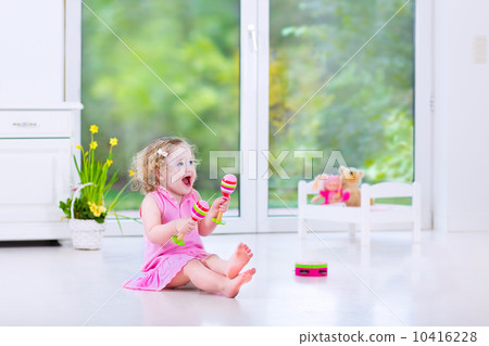 Cute curly toddler girl playing tambourine in a sunny white room Cute curly toddler girl playing tambourine in a sunny white room 10416228