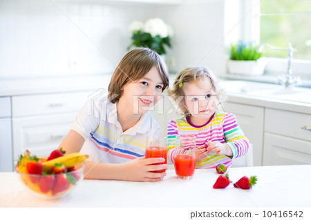 Happy teenager boy and his cute toddler sister having fruit for 10416542