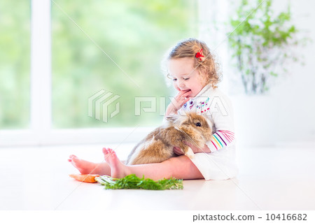 Adorable toddler girl with beautiful curly hair wearing a white 10416682