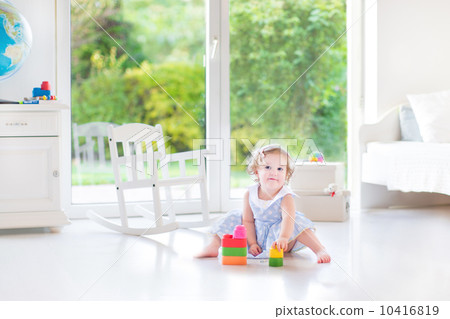 Adorable toddler girl with curly hair wearing a blue dress playi Adorable toddler girl with curly hair wearing a blue dress playi 10416819