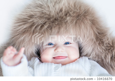 Funny cute baby girl with big blue eyes wearing a huge winter ha Funny cute baby girl with big blue eyes wearing a huge winter ha 10416870