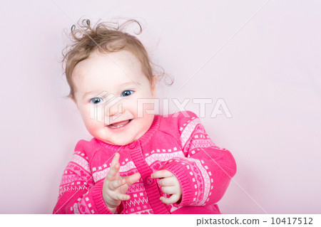 Cute baby girl in a pink knitted sweater with hearts pattern on a pink blanket Cute baby girl in a pink knitted sweater with hearts pattern on a pink blanket 10417512