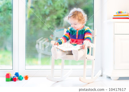 Adorable toddler girl with curly hair wearing a colorful knitted Adorable toddler girl with curly hair wearing a colorful knitted 10417617