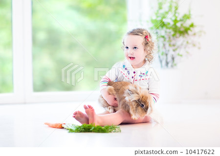 Adorable toddler girl with beautiful curly hair wearing a white 10417622