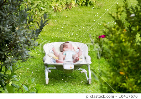 Newborn baby sleeping in a bouncer in the garden 10417676