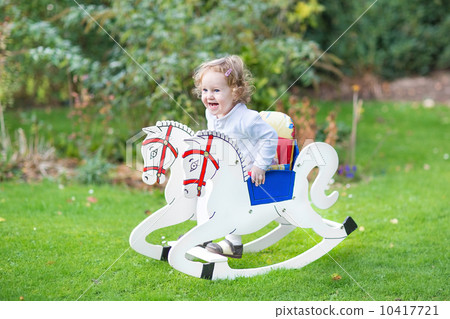Cute happy litlte girl on a rocking horse in the garden 10417721
