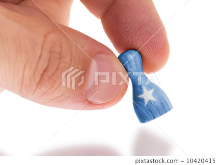Hand holding wooden pawn, flag painting, selective focus Hand holding wooden pawn, flag painting, selective focus 10420415
