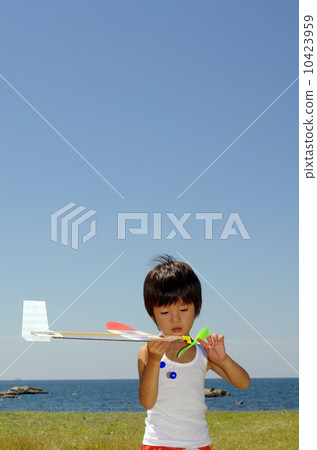 Children flying a model plane on the coast 10423959