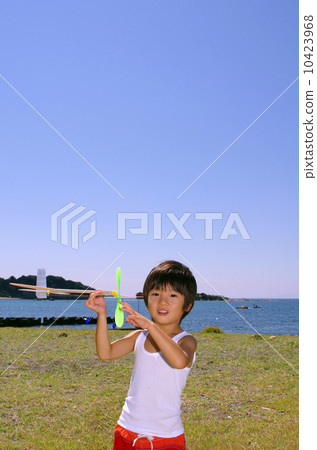 Children flying a model plane on the coast 10423968