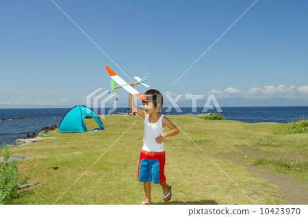 Children flying a model plane on the coast 10423970