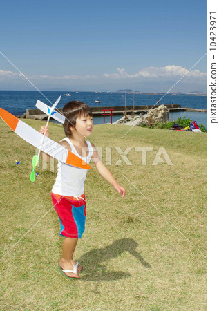 Children flying a model plane on the coast 10423971