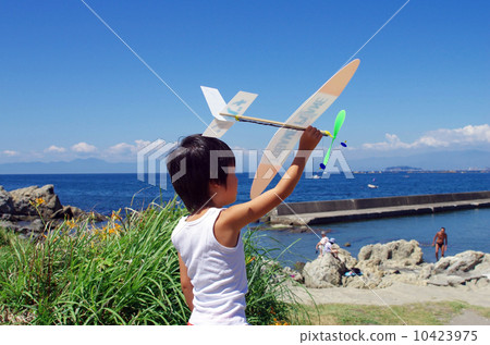 Children flying a model plane on the coast 10423975