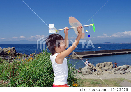 Children flying a model plane on the coast 10423976